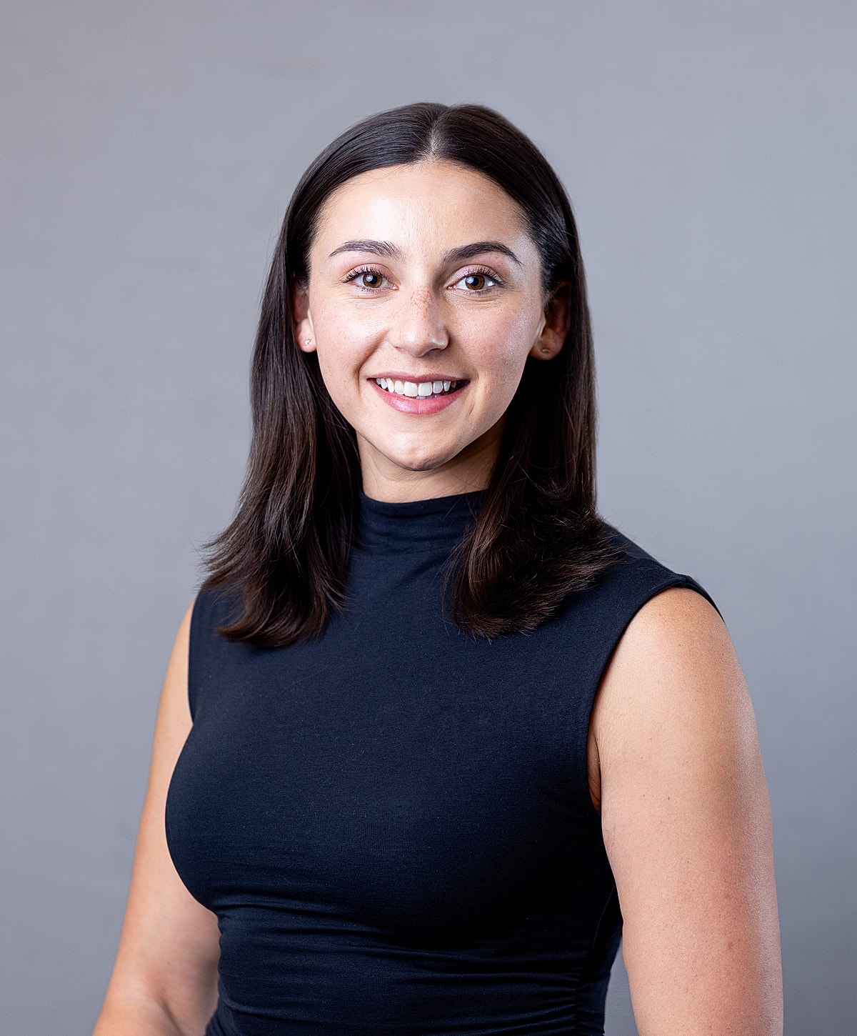 Woman smiling in a black sleeveless top.