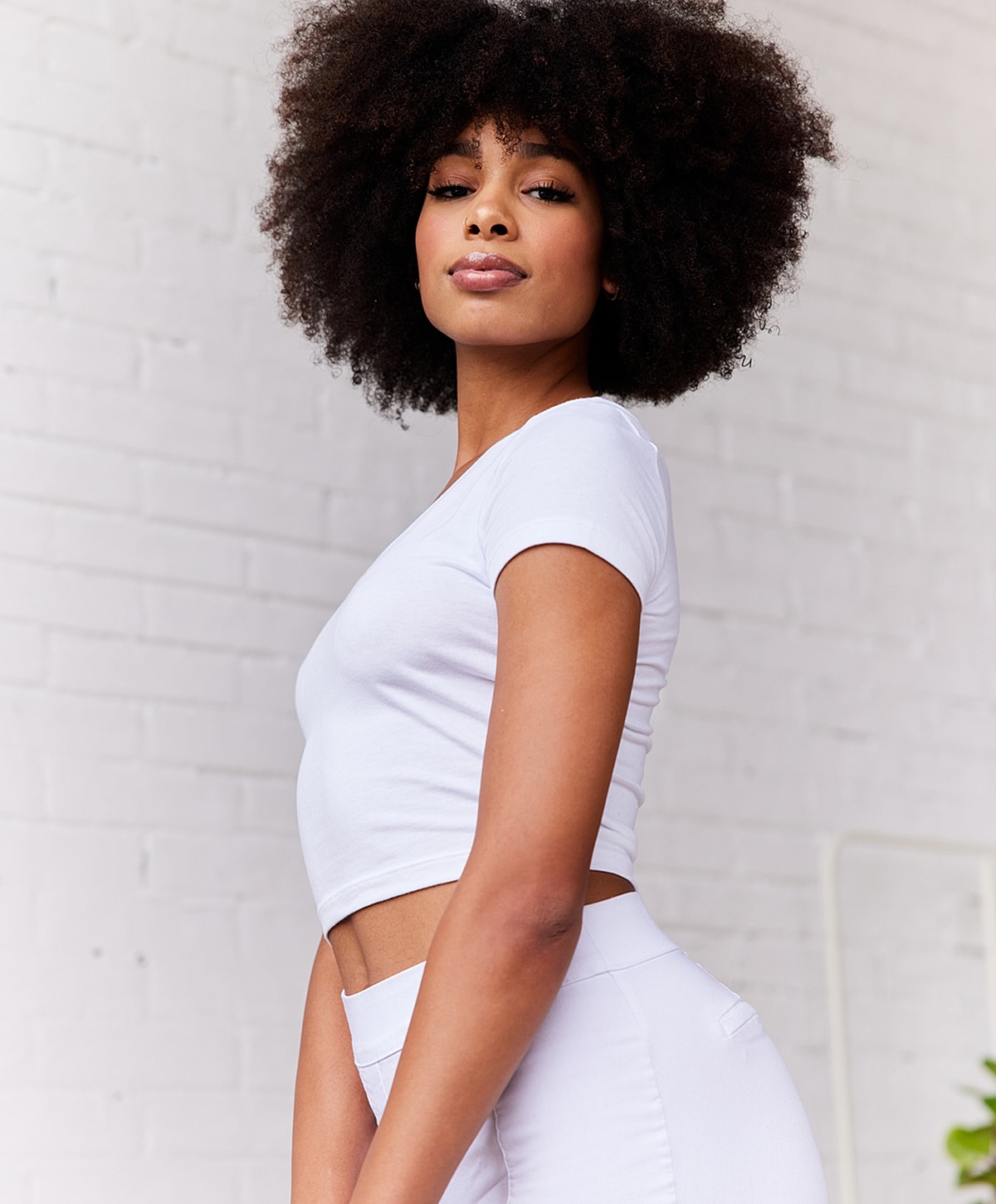 Model with curly hair in white outfit.