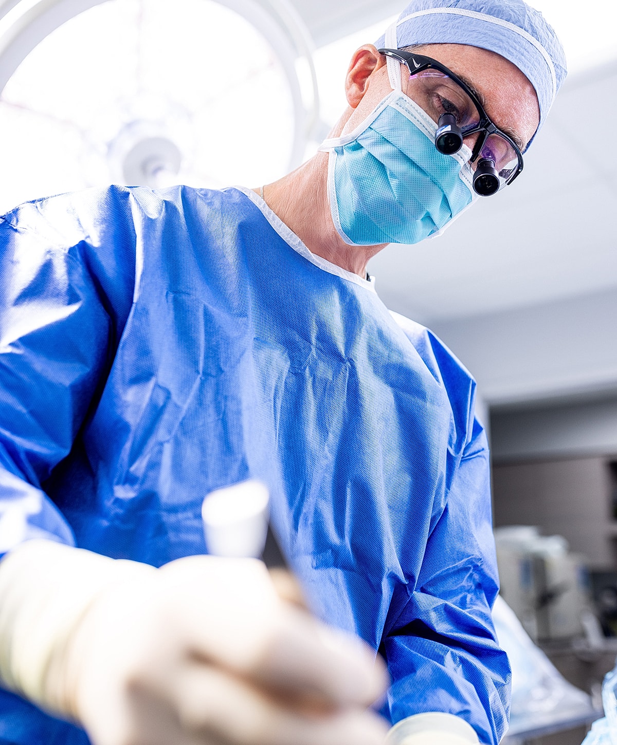 Surgeon in blue scrubs performing a procedure.