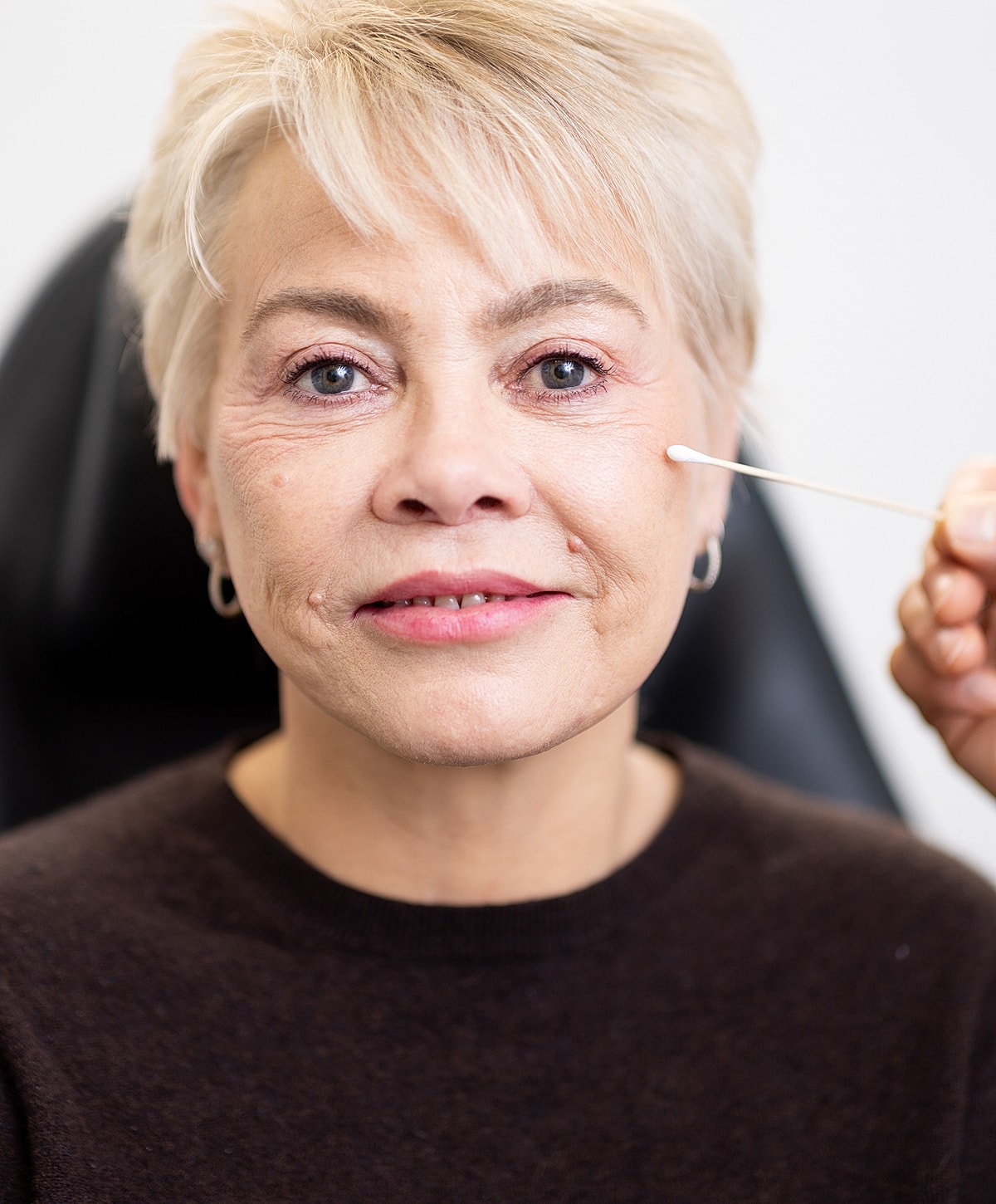 Woman receiving facial treatment with cotton swab.
