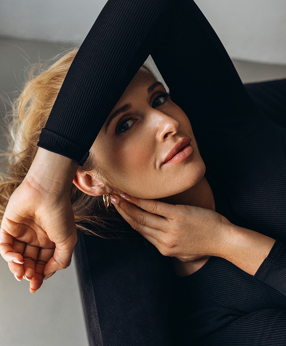 Woman with hand on face, relaxed pose, natural light.