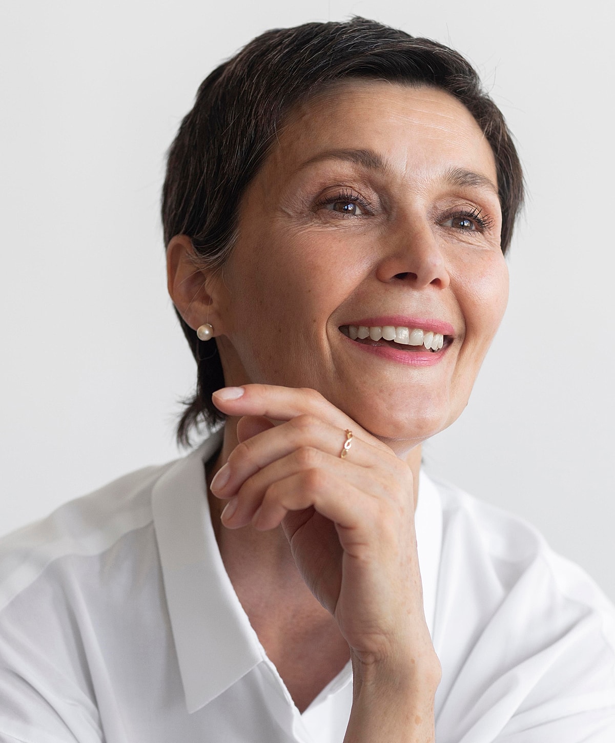 Smiling woman with short hair and earrings.