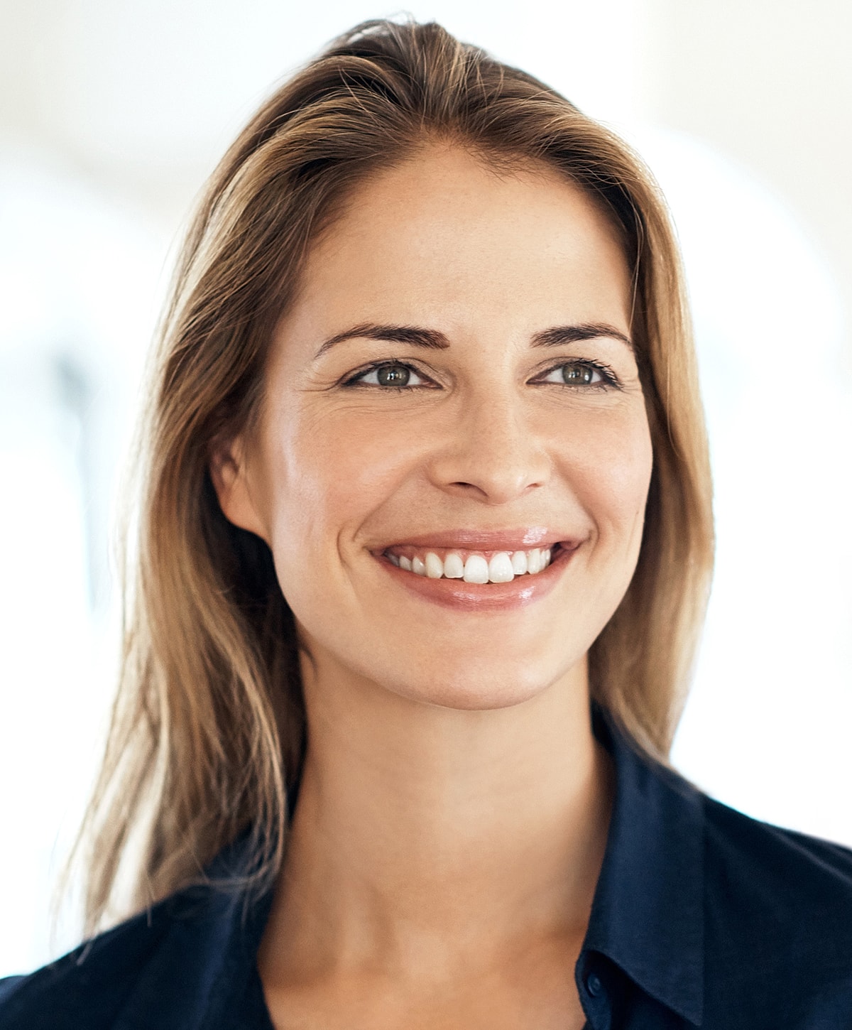 Smiling woman with long, straight hair indoors.