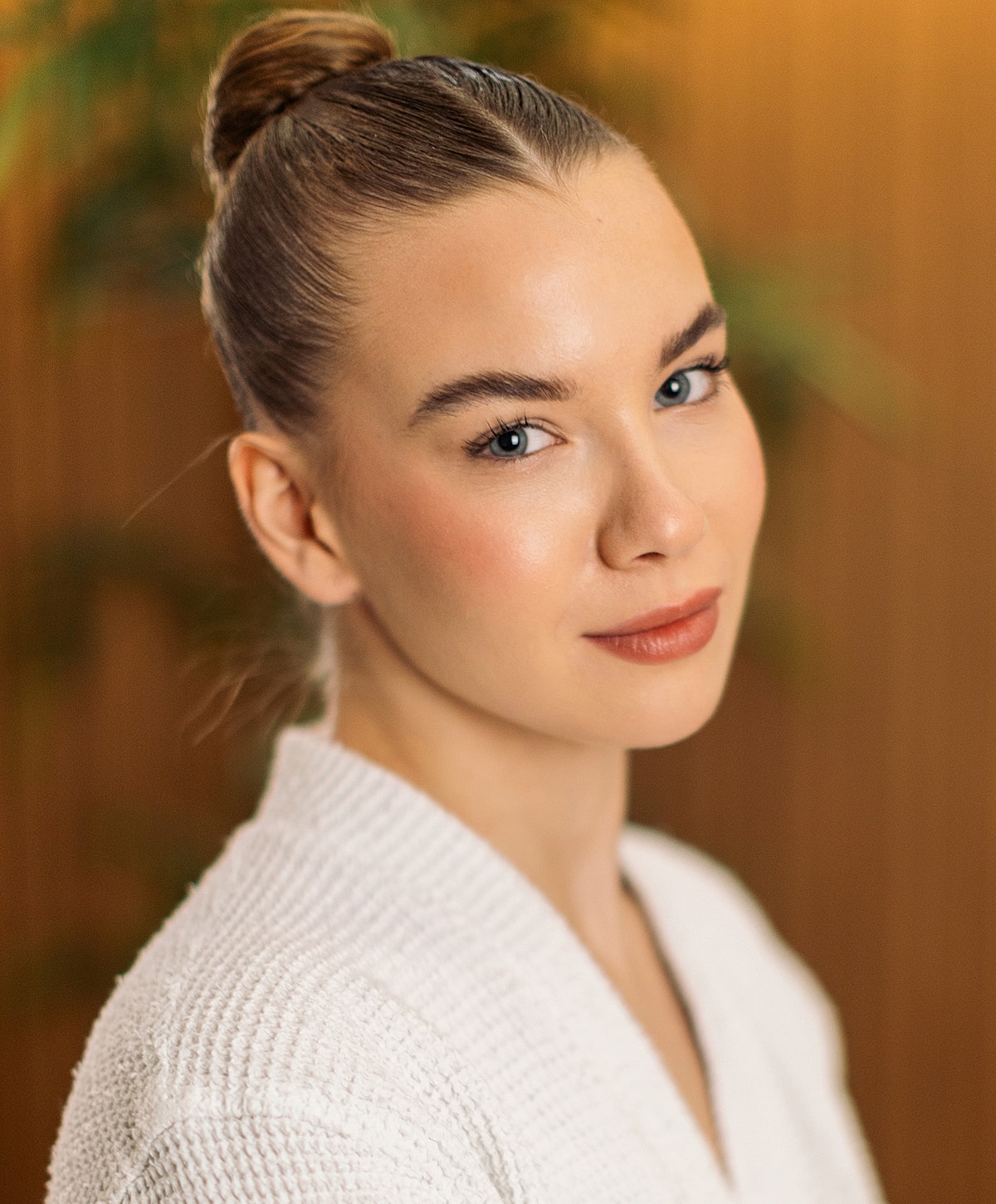 Woman with a bun, serene expression, natural makeup.