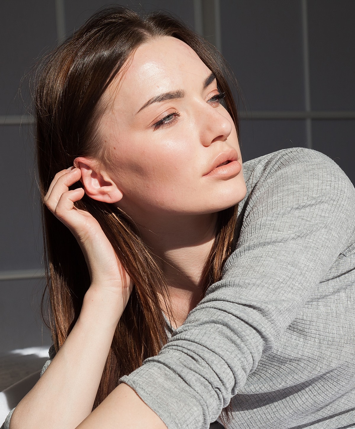 Woman in sunlight with relaxed expression.