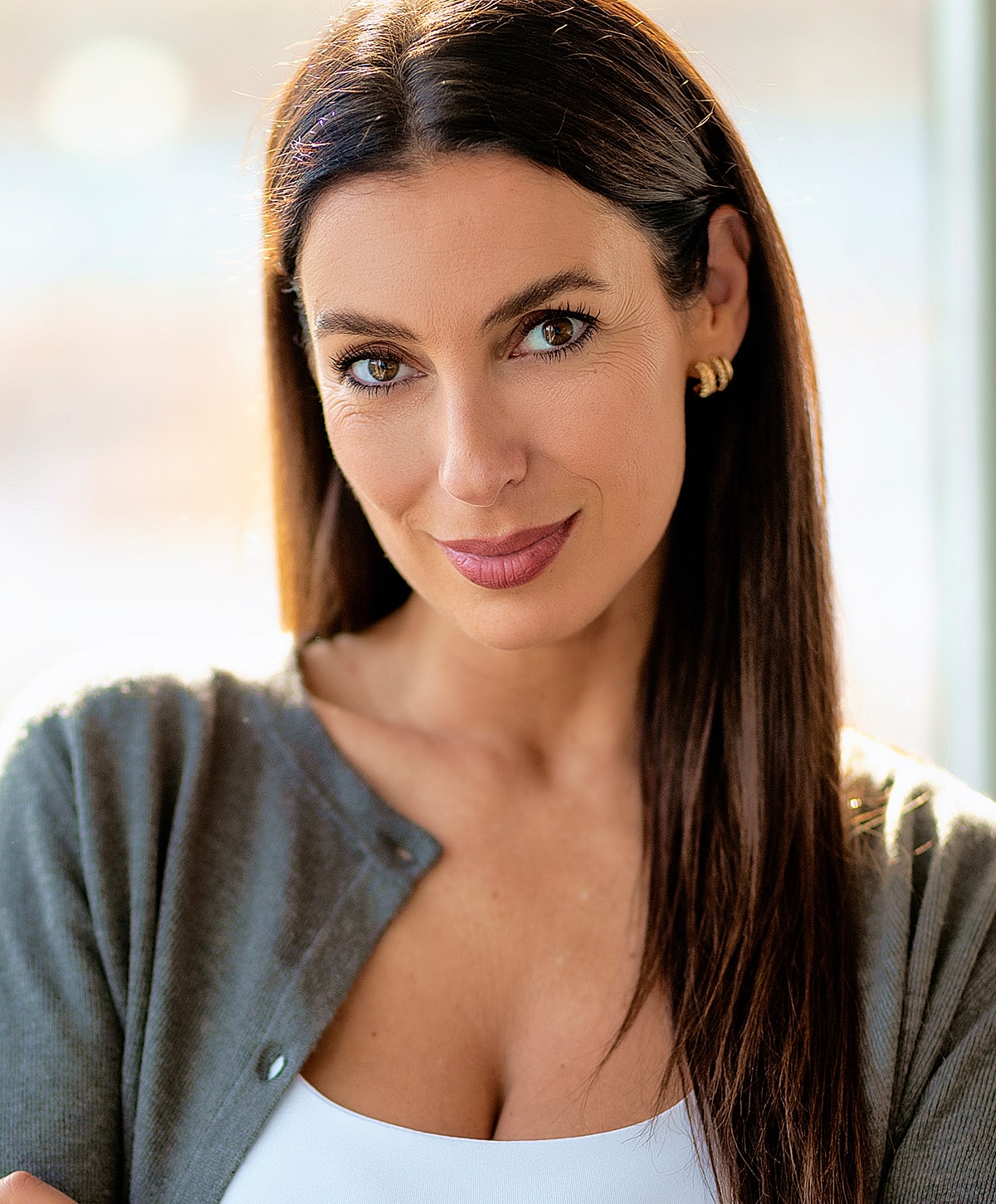 Woman smiling with long hair and cardigan.