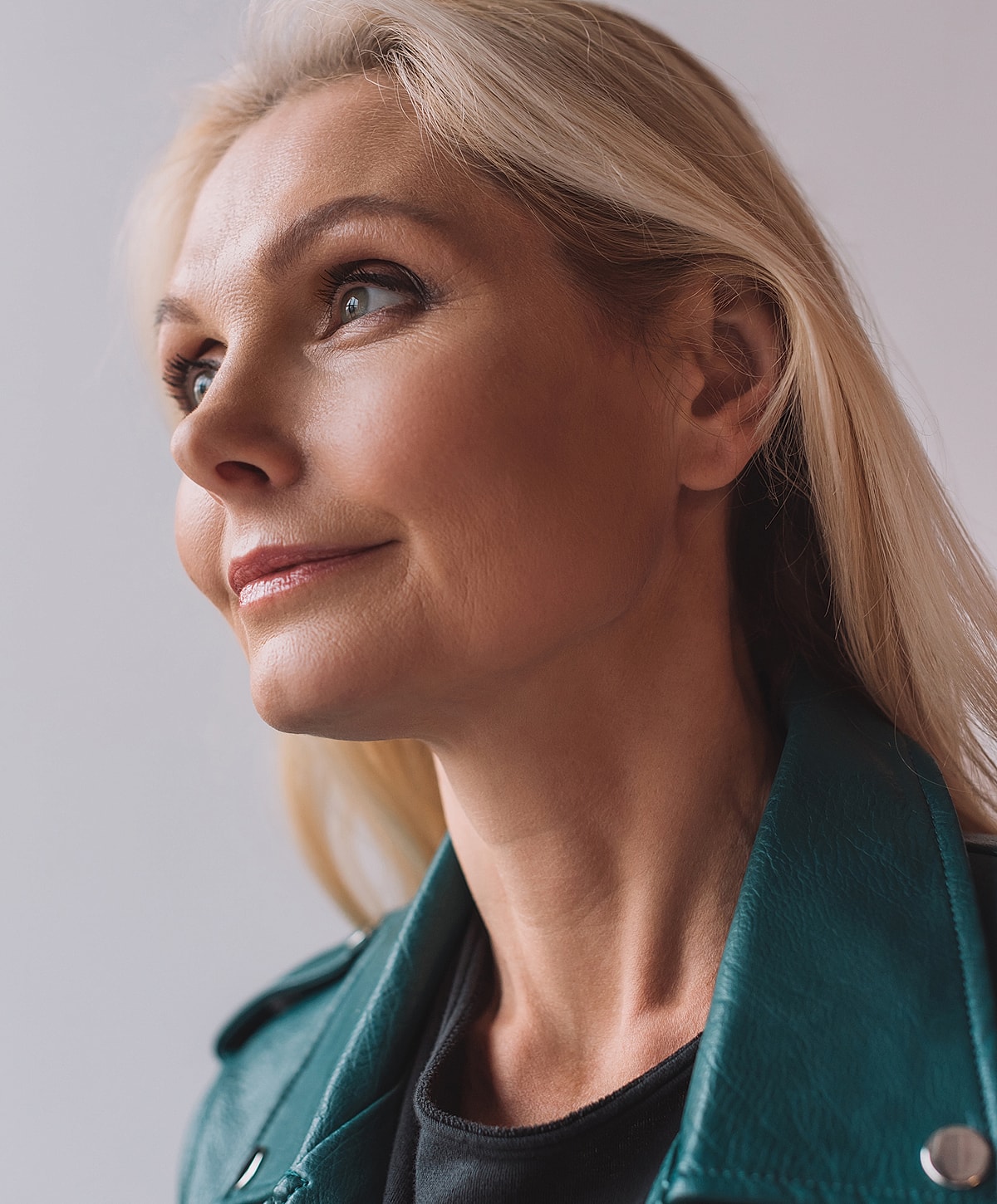 Woman with blonde hair in a teal jacket.