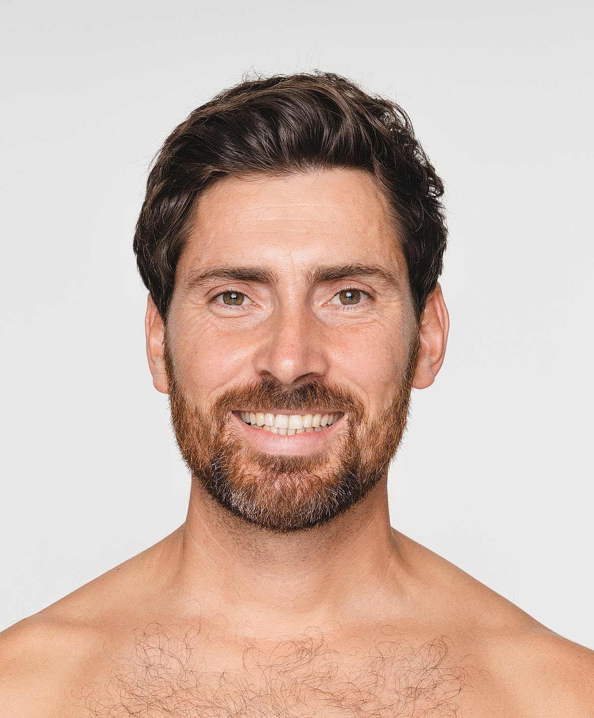 Smiling man with beard, neutral background.
