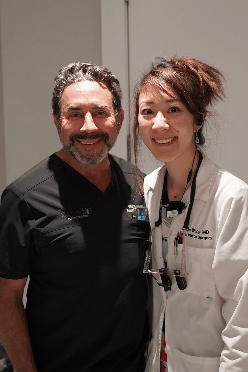 Two plastic surgeons posing together, smiling.