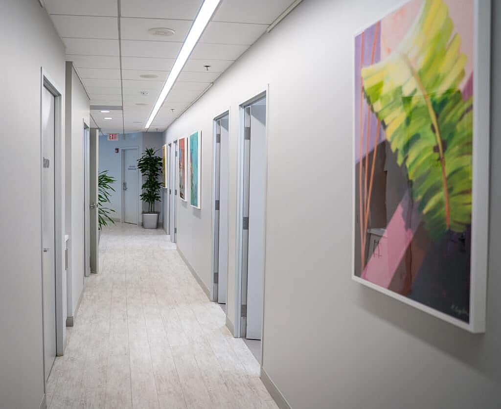 Modern hallway with artwork and greenery.