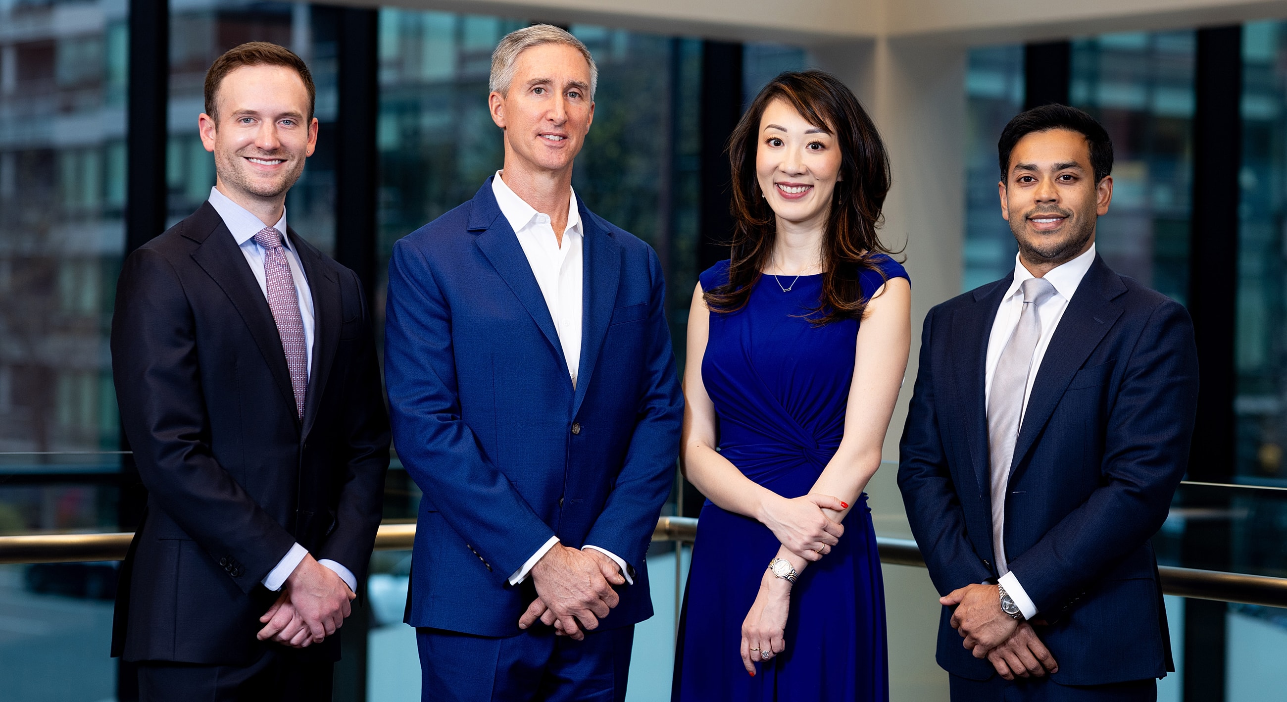 Four professionals posing indoors in business attire.