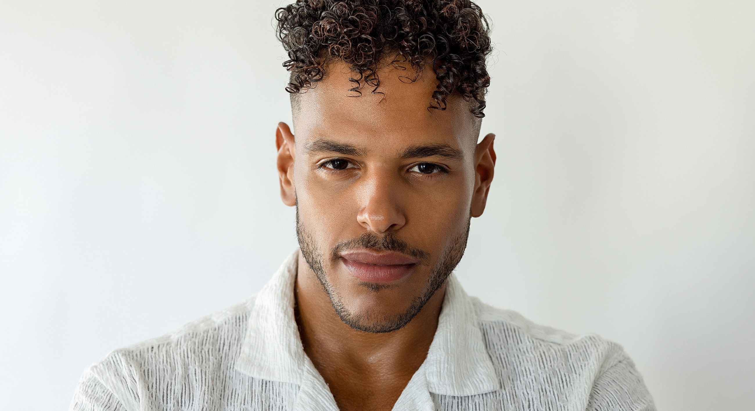 Man with curly hair in white shirt.
