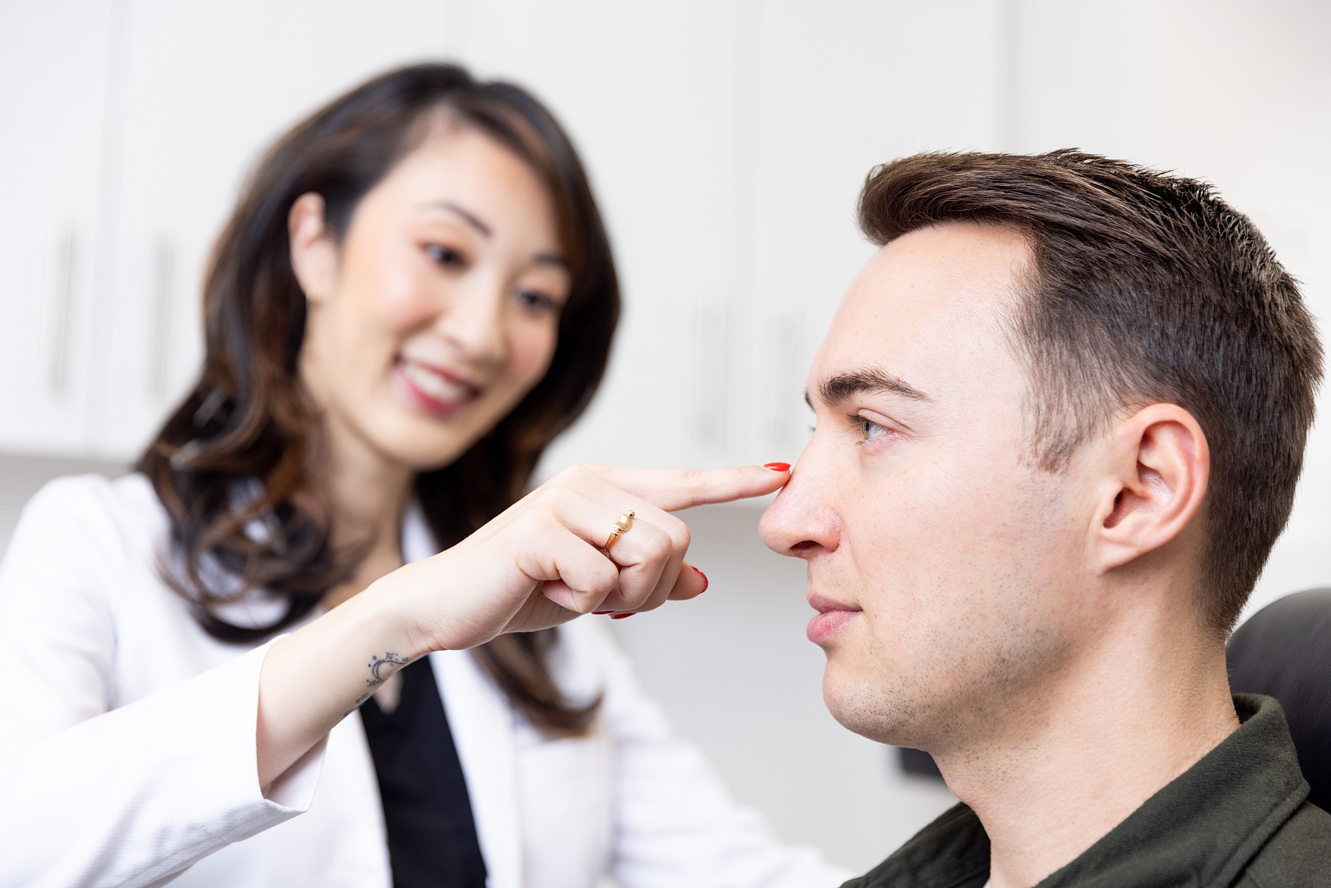 Doctor examining a patient's nose in clinic.