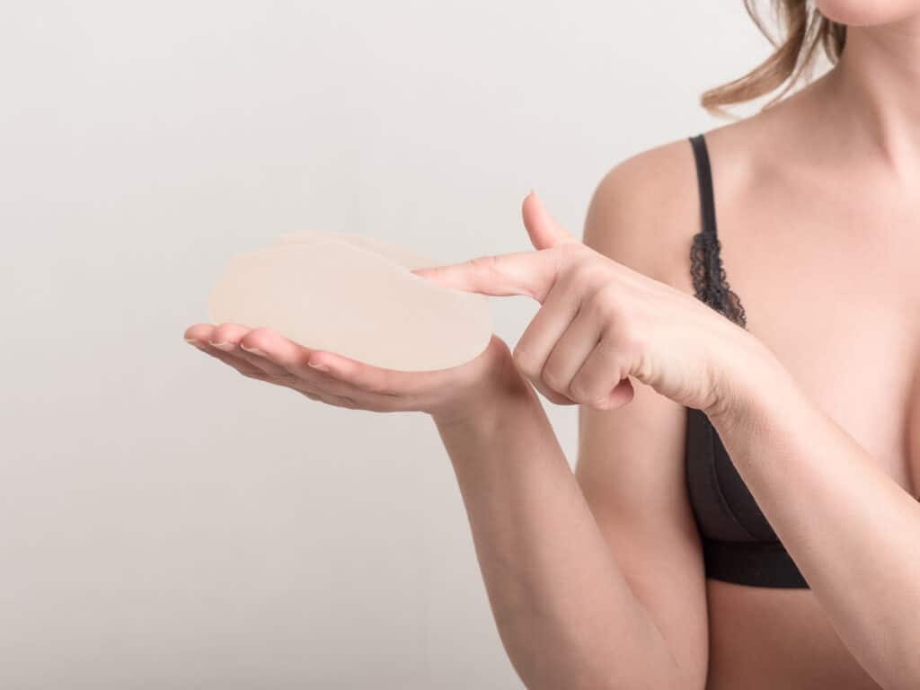 A close-up shot of a woman holding a breast implant in her hand