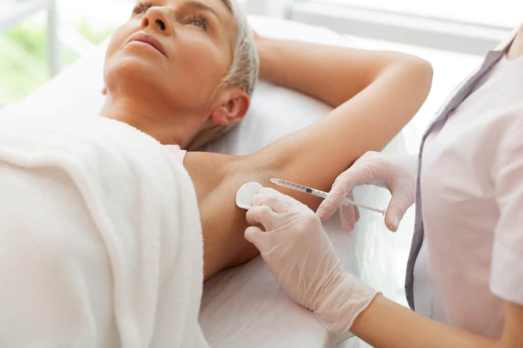 Woman receiving Botox injections into her armpits to combat hyperhidrosis or excessive sweating