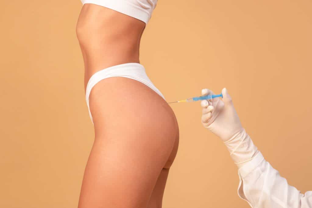 Woman receiving a non-surgical butt lift injection into her rear from her plastic surgeon