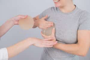 Caucasian woman trying on breast implants. A plastic surgeon helps a patient with a choice.